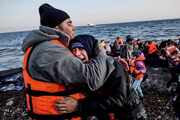 A father comforts his crying son shortly after arriving on the shores of Lesbos, Greece, on 17 November 2015