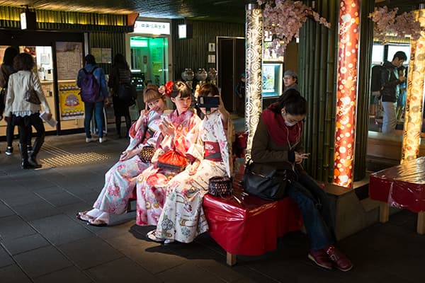Girls dressed in kimonos take a selfie at Arashiyama train station near Kyoto, Japan