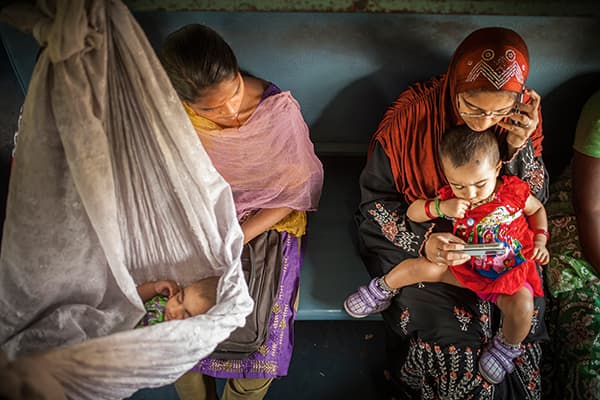 Young women with their children in the ladies’ compartment of a local train. The child sleeps in a makeshift hammock